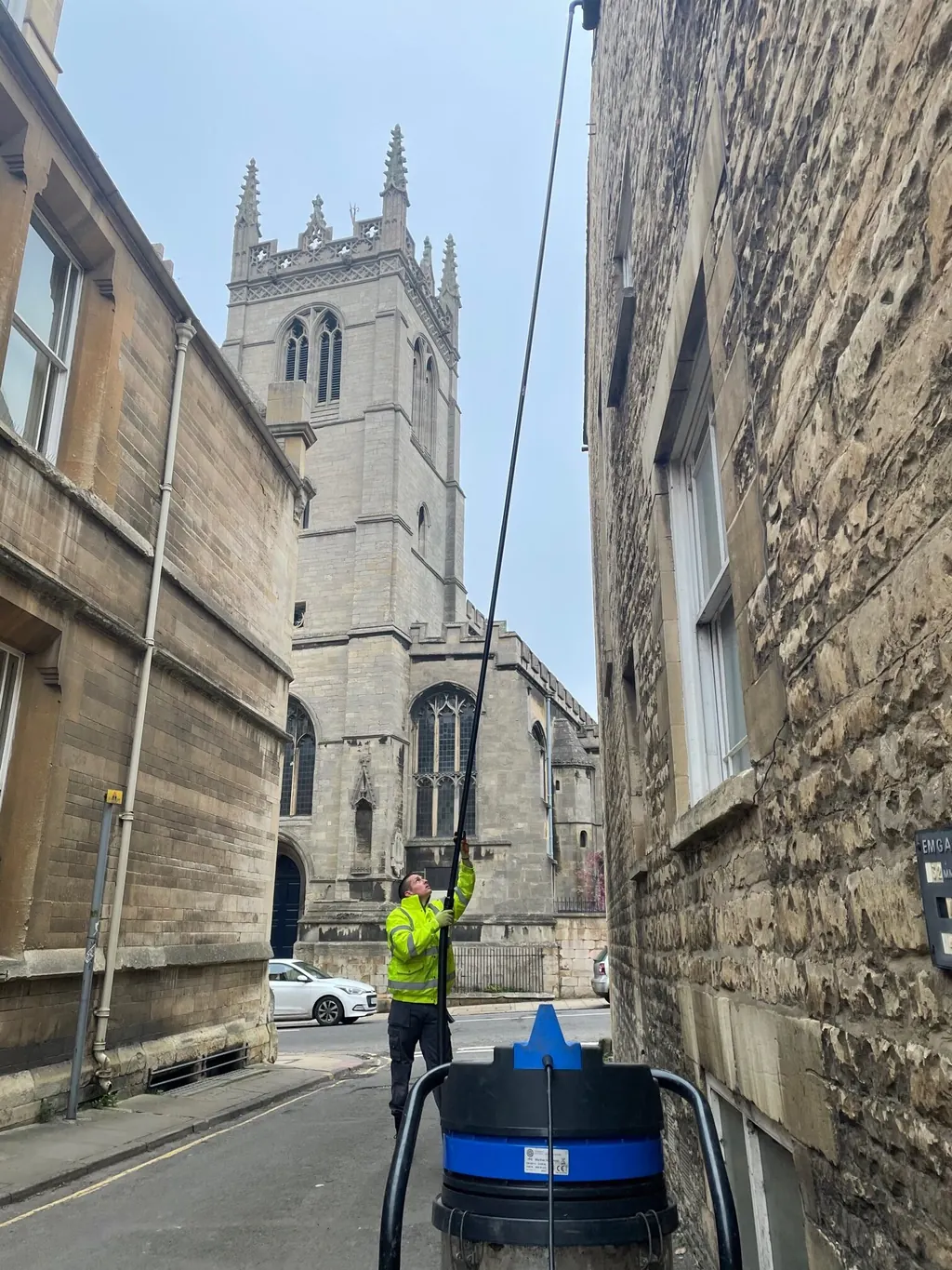 Lanes Ltd operative cleaning tall windows with a water-fed pole in a town centre